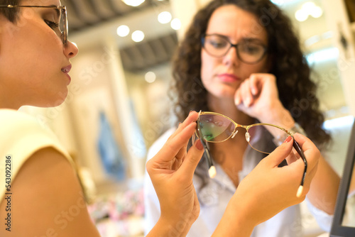 Young beautiful woman choosing eyeglasses in optical shop