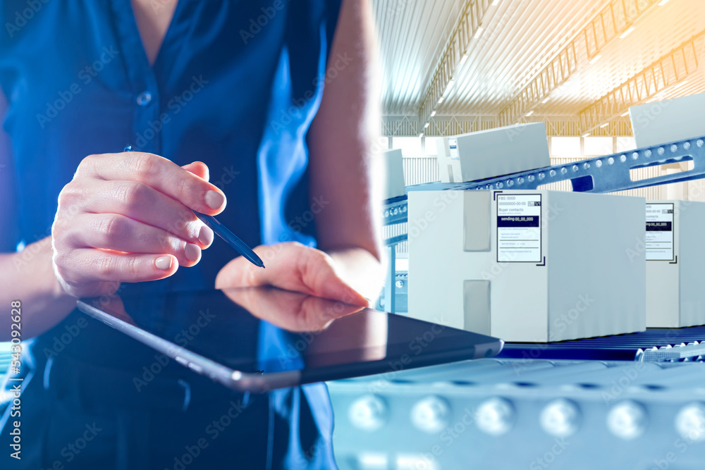 Warehouse manager with tablet. Conveyor with boxes behind woman. Girl