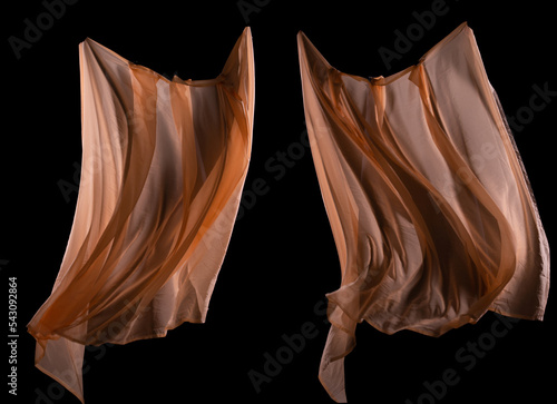 Set with beautiful delicate orange silk like floating in air. Smooth elegant pink transparent cloth fluttering throwing and wave drapes over black background isolated. Texture of flying fabric.