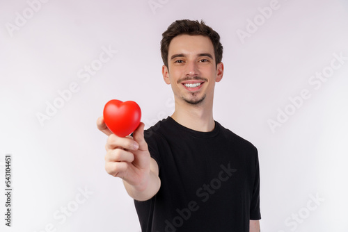 Portrait of Happy young caucasian man wearing black T-shirt is holding a red apple on isolated background
