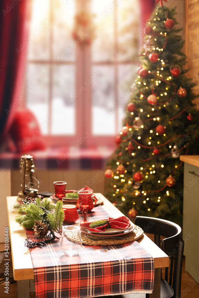 Christmas and New Year 2023, a beautiful setting of the New Year's table in red, against the background of a decorated Christmas tree and a window with a winter landscape Christmas and New Year 2023, a beautiful setting of the New Year's table in red, against the background of a decorated Christmas tree and a window with a winter landscape
