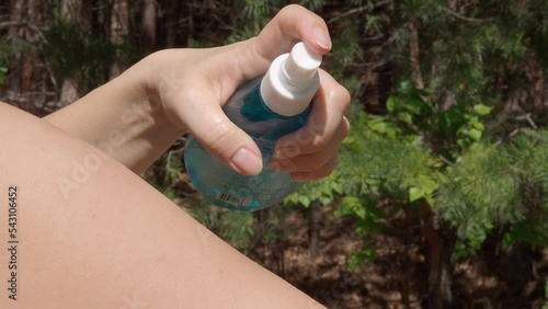 Close-up girl spraying sunscreen spray on shoulder. Summer forest background