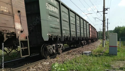 Freight train rides on rails in summer. Cargo wagons containers move fast