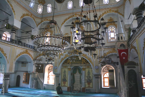 A very old mosque in the center of Izmir offers a surprisingly fancy decoration with floral motifs. There is little of the usual calligraphy. 2 worshippers pray in front of the prayer niche in the dir photo