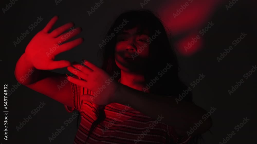 Woman Shielding Face With Hands While Standing In Low Red Light. close up Woman Shielding Face With Hands While Standing In Low Red Light. close up