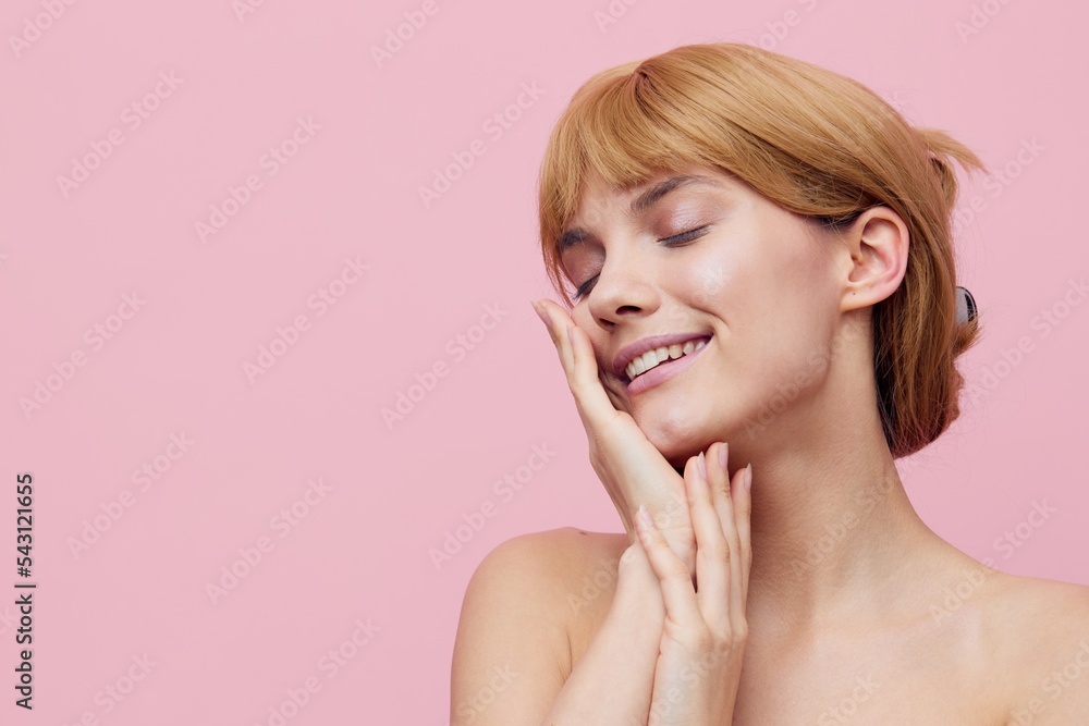 a close horizontal photo of a pleasant, lovely woman with perfect skin standing on a pink background gently touching her face with her hands, closing her eyes with pleasure a close horizontal photo of a pleasant, lovely woman with perfect skin standing on a pink background gently touching her face with her hands, closing her eyes with pleasure