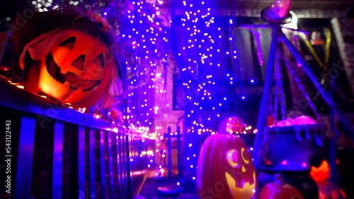 Halloween installation at Dyker Heights: funny plastic pumpkins - Jacks O'Lanterns, cauldron with magic potion on the background, blue glowing lights photo