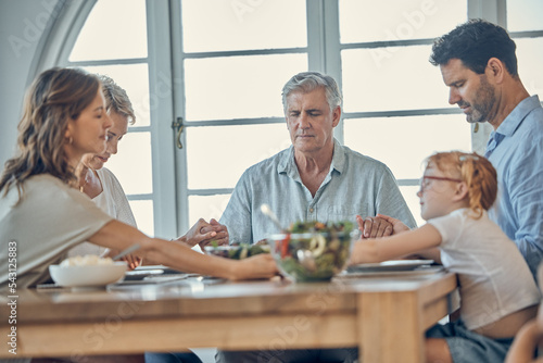 Big family, food and praying for gratitude and healthy lunch together while holding hands for love, religion and thanksgiving. Men, women and child together for healthy eating at home dining table