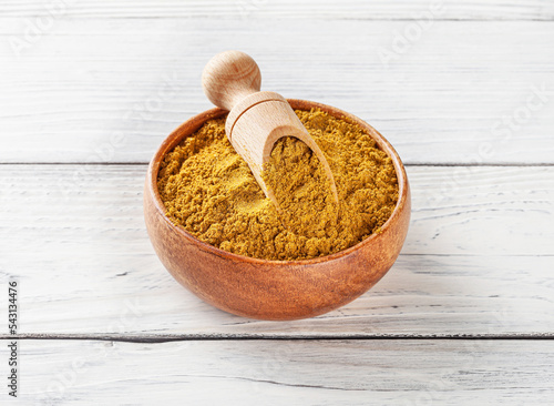 Obraz na płótnie Curry powder in wooden bowl with scoop on white wooden background w salonie