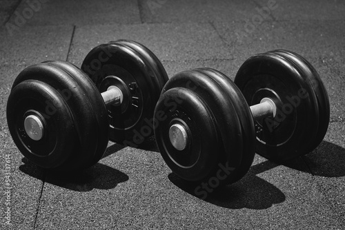 Fototapeta Naklejka Na Ścianę i Meble -  dumbbell on the rubber floor in the gym, black and white photography. Bodybuilding equipment. Fitness or bodybuilding concept background.
