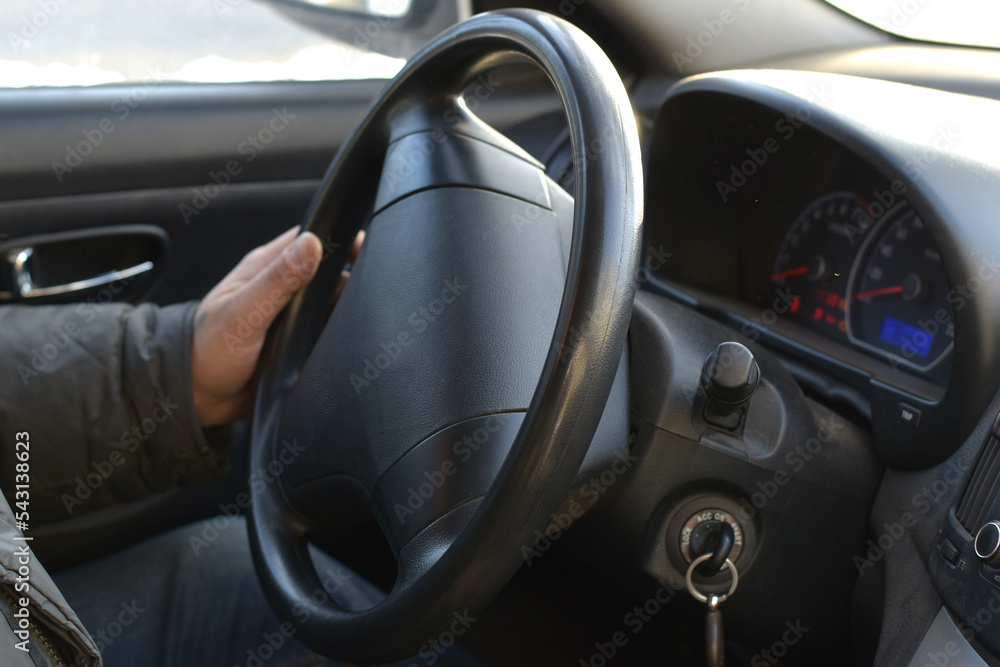 View of the car interior, the driver's hand on the steering wheel.