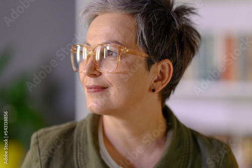 Profile portrait of middle aged mature grey haired woman. Close up of attractive happy woman in glasses looking beside. Portrait of positive single senior female. © ReyRomMedia