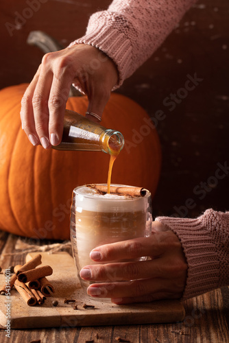 Woman hand holding homemade pumpkin spice latte made from scratch with pumpkin spice syrup