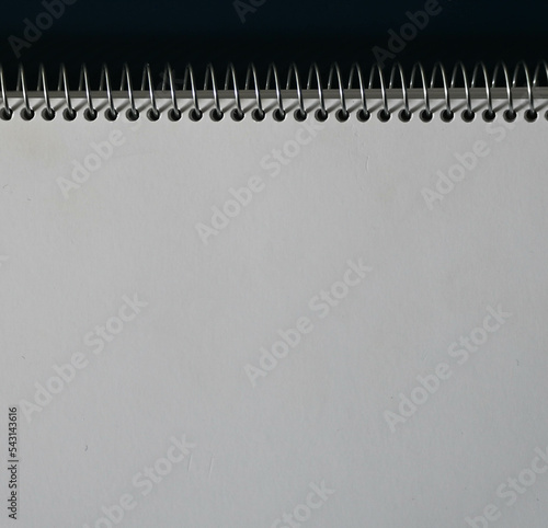 Fondo con detalle y textura de libreta con espiral metalica, sobre fondo de tonos oscuros
