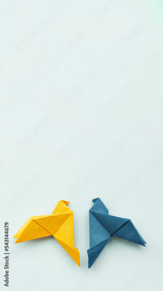 two doves made of origami paper in yellow and blue, in colors of Ukrainian flag on background, vertical, 16:9, two doves made of origami paper in yellow and blue, in colors of Ukrainian flag on background, vertical, 16:9,