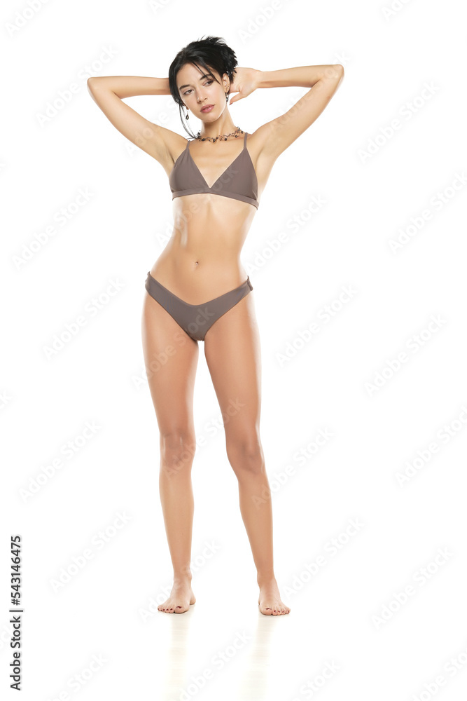 Young brunette woman in bikini swimsuit posing on a white background. Young brunette woman in bikini swimsuit posing on a white background.