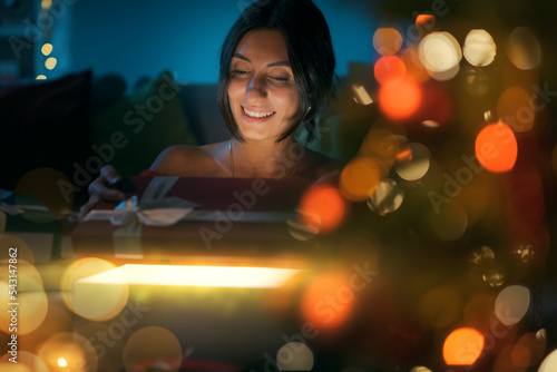 Happy woman opening Christmas gifts at home