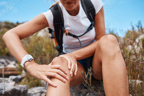 Hiking, injury and woman with knee pain emergency in nature from a mountain trekking adventure journey. Healthy, fitness and injured woman with leg problem after suffering in an accident outdoors