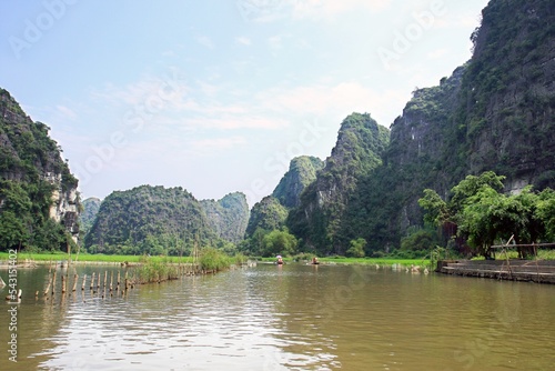 Tourists traveling in boat along the Ngo Dong River, Landscape formed by karst towers and rice fields, in Ninh Binh - Vietnam