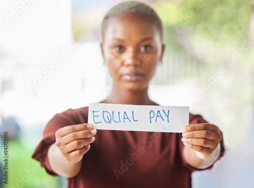 Equal pay, paper sign and black woman protest for women work salary rights outdoor. Portrait of a young person from Africa with serious protesting for female worker empowerment and equality photo