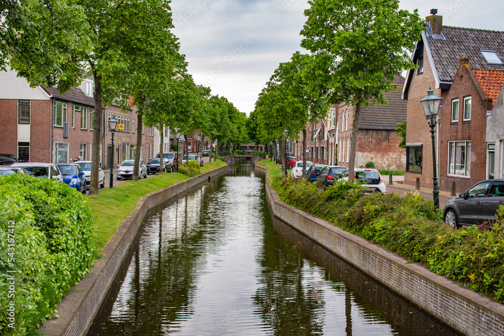 Road and brick houses by a canal in the Netherlands. Summer. Road and brick houses by a canal in the Netherlands. Summer.