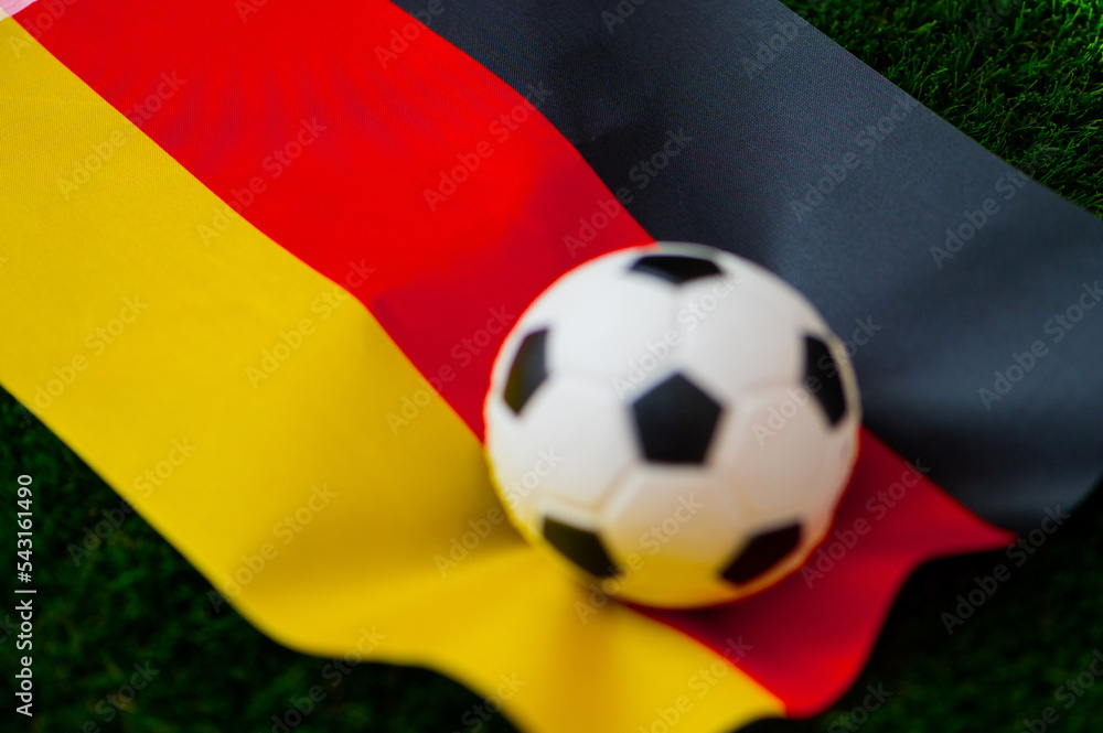 Naklejka premium Germany national football team. National Flag on green grass and soccer ball. Football wallpaper for Championship and Tournament in 2022. World international match.