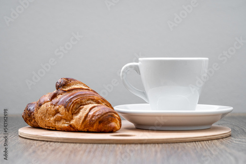 coffee and croissant on a wooden tray on the table