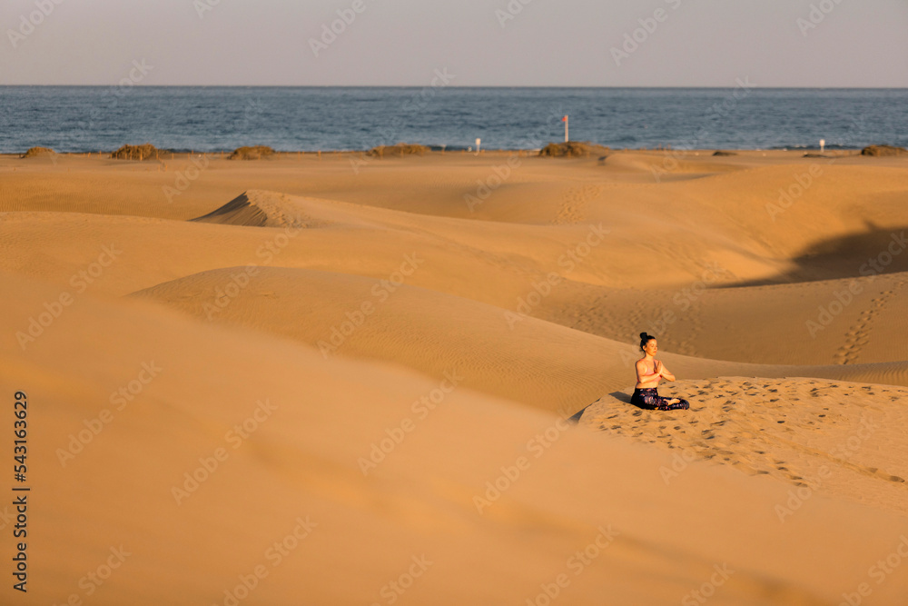 Anonymous woman sitting on sandy beach