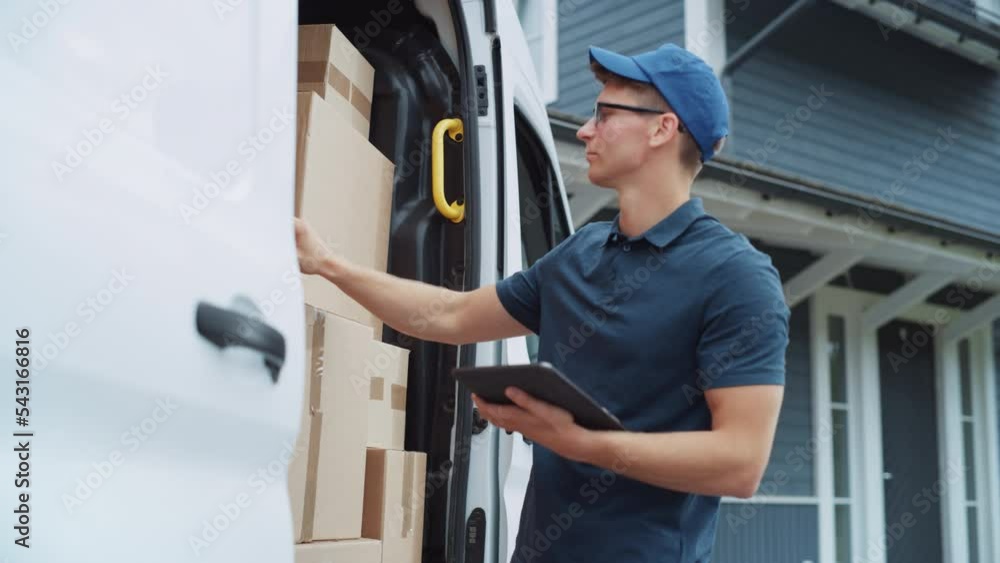 Young Man Working in Delivery Services, Using Tablet Computer to Find the Parcel. Mailman Taking Out a Cardboard Box From a White Delivery Vehicle and Bringing the Box to the Homeowner. Young Man Working in Delivery Services, Using Tablet Computer to Find the Parcel. Mailman Taking Out a Cardboard Box From a White Delivery Vehicle and Bringing the Box to the Homeowner.