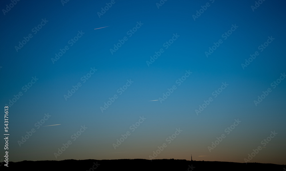 Mountain silhouette with communication antenna and plane trails