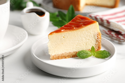 Piece of delicious caramel cheesecake served on white marble table, closeup