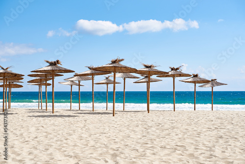 Beach wooden umbrellas on sand by sea