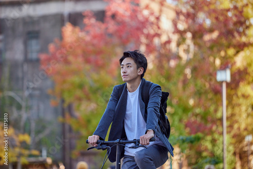 自転車に乗るジャケットを着た若い日本人の男性