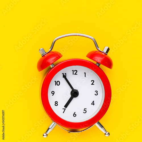 Red alarm clock on a yellow background.