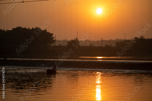 Sun Shine Over Blue Water Lake Or River At Sunrise. Nature At Sunny Morning. Woods With Orange Foliage On Riverside  Beautiful  colorful sunrise over a wide river. 