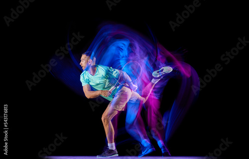 Studio shot of professional tennis player playing tennis isolated over dark background in mixed neon light. Concept of motion, speed, professional sport. © master1305