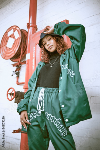 Fashion, wall and black woman with green clothes, fashionable style or cool hip hop outfit. Fire hose, attitude or portrait of gen z girl with trendy streetwear, designer brand or 2000s rap aesthetic photo