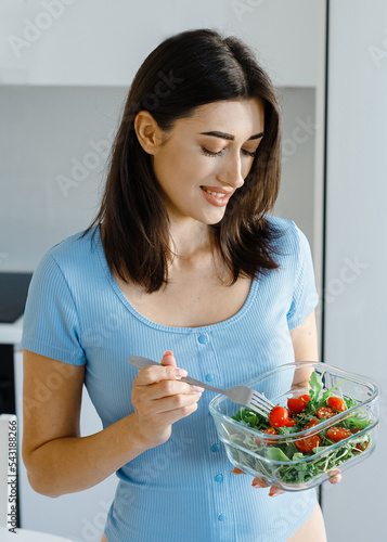 Young happy woman eating healthy salad.Smiling female dietitian sitting at the table with colorful fruits and vegetables in clinic. Concept of diet, lose weight and healthcare.  . High quality photo photo