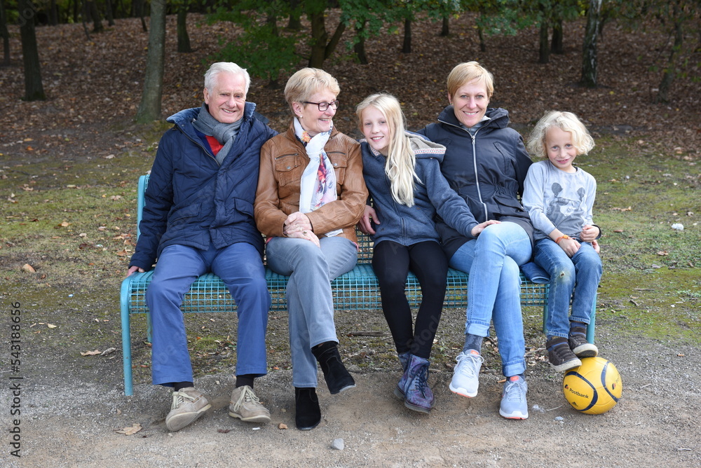 Familie mit Großeltern auf einer Bank im Park