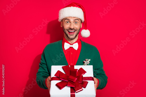 Photo of charming impressed man wear x-mas bowtie green cardigan holding noel present isolated red color background
