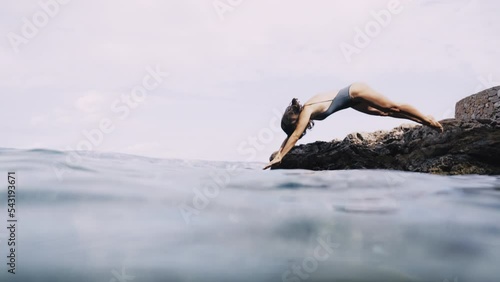 Slow motion shot of girl jumping into the sea following her underwater