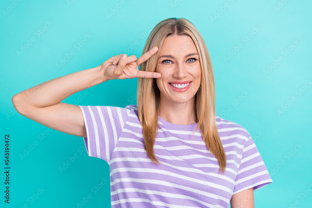 Photo of good mood optimistic nice woman with straight hairstyle wear striped t-shirt showing v-sign isolated on blue color background Photo of good mood optimistic nice woman with straight hairstyle wear striped t-shirt showing v-sign isolated on blue color background