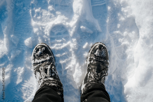 Man in black pants and winter boots standing in the snow outdoors, close-up. Top view, first person view