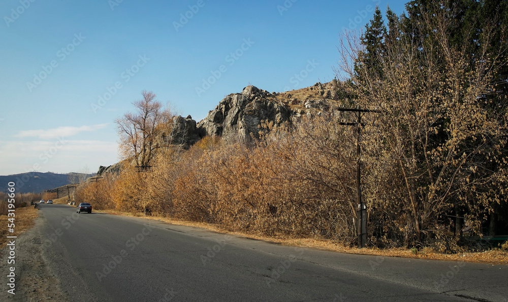 Asphalt road. Autumn landscape. Yellow trees and blue sky. Rocky mountains. Ust-Kamenogorsk (kazakhstan) Asphalt road. Autumn landscape. Yellow trees and blue sky. Rocky mountains. Ust-Kamenogorsk (kazakhstan)