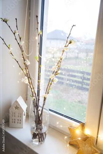 Blooming cherry branches with garland in a glass vase