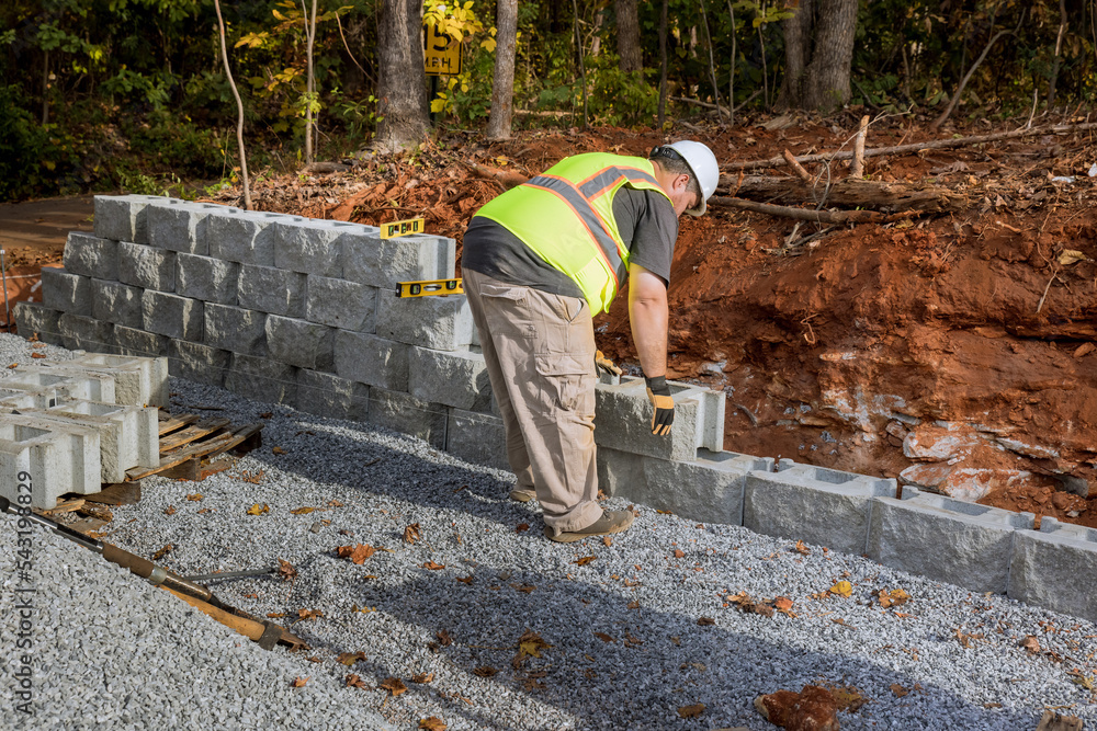 Construction worker building retaining block wall being built on new property Construction worker building retaining block wall being built on new property