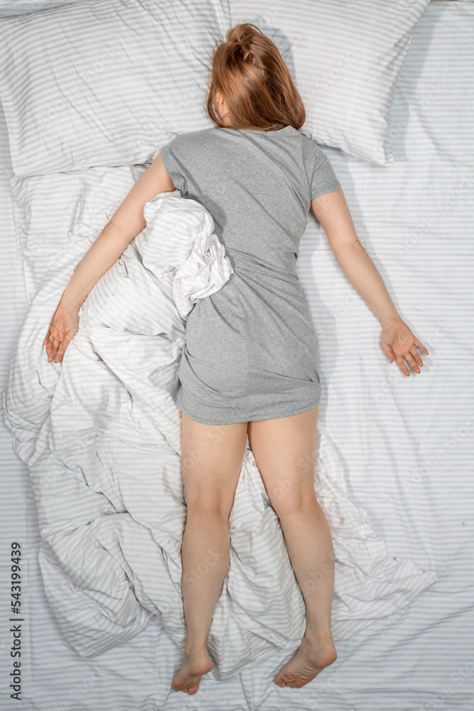 Woman sleeping face down on stomach in bed at home. Deep sleep. Lady