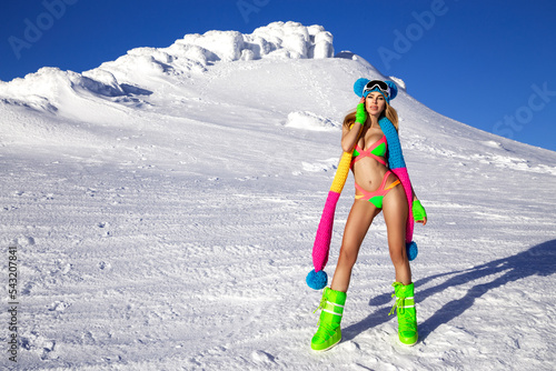 Sexy woman in a colorful bikini, beanie and winter boots is posing in the mountains. Winter fashion model. Female model in bikini. Bikini challenge
