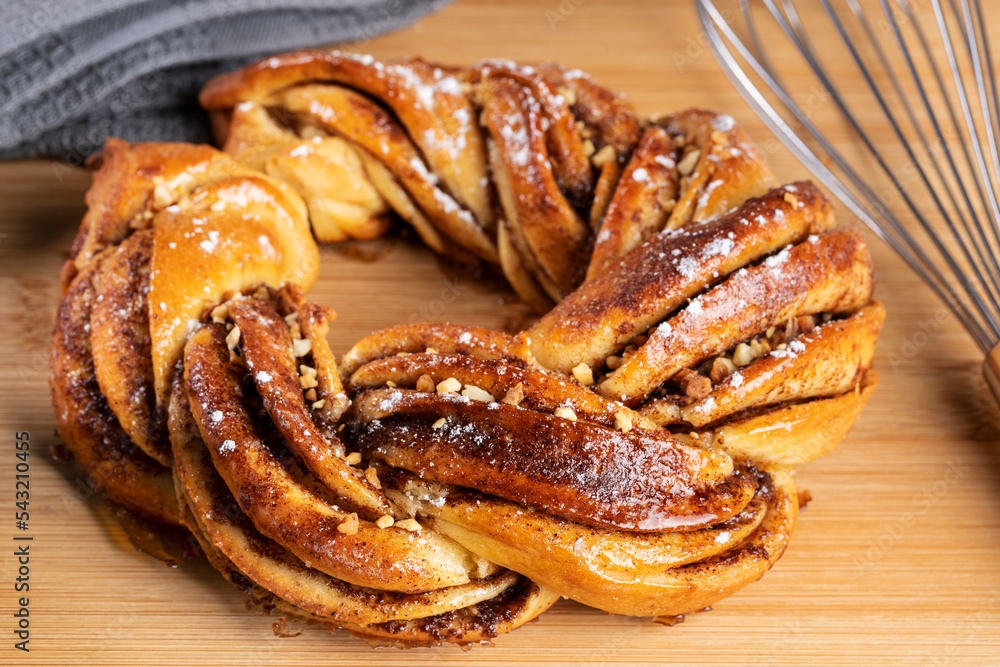 Roscón de reyes Kringle Estonia. Typical Christmas sweet, braided sponge cake with cinnamon, butter, walnuts or almonds and icing sugar on a white background. Roscón de reyes Kringle Estonia. Typical Christmas sweet, braided sponge cake with cinnamon, butter, walnuts or almonds and icing sugar on a white background.