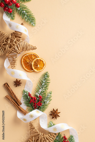 Christmas concept. Top view vertical photo of wicker stars dried orange slices cinnamon sticks mistletoe curly ribbon fir branches in hoarfrost and anise on isolated beige background with copyspace